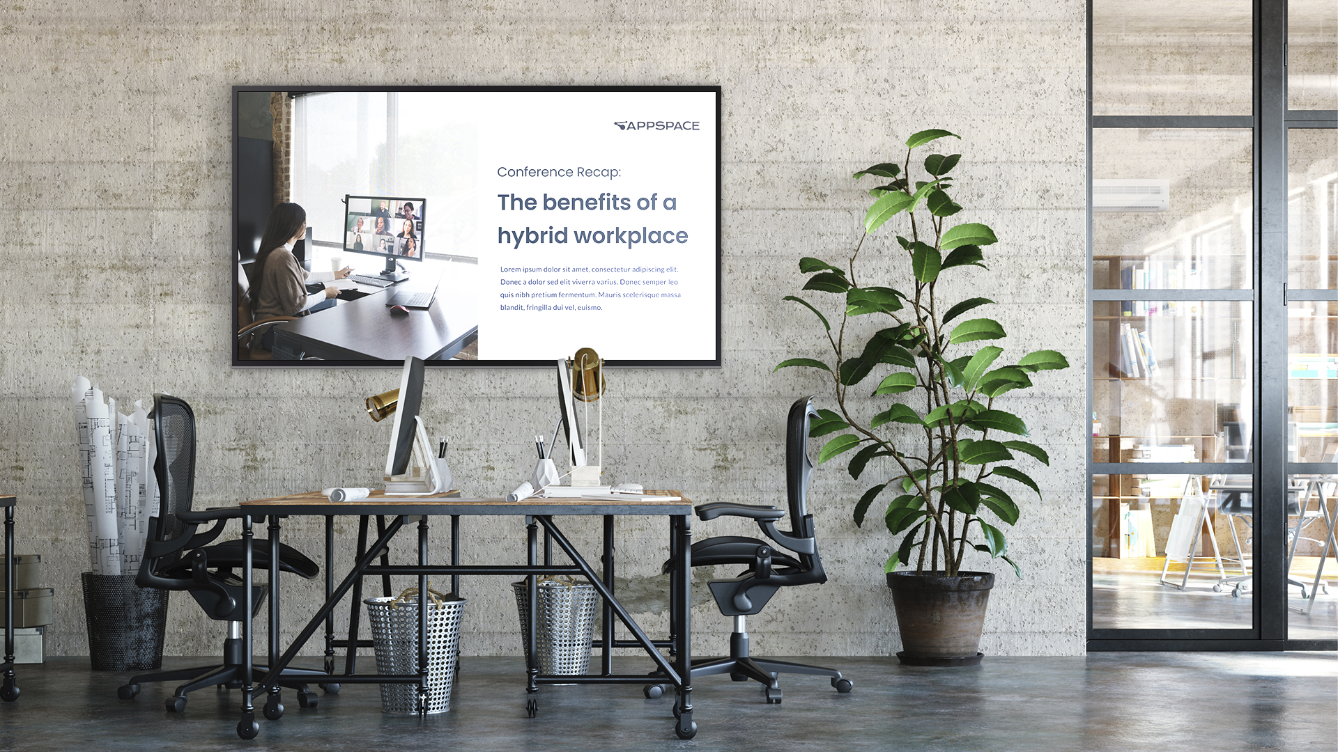 Modern office with two desks, each with computers and lamps, facing a large screen on the wall displaying The benefits of a hybrid workplace. A large potted plant is beside the desks, and a glass partition is in the background.
