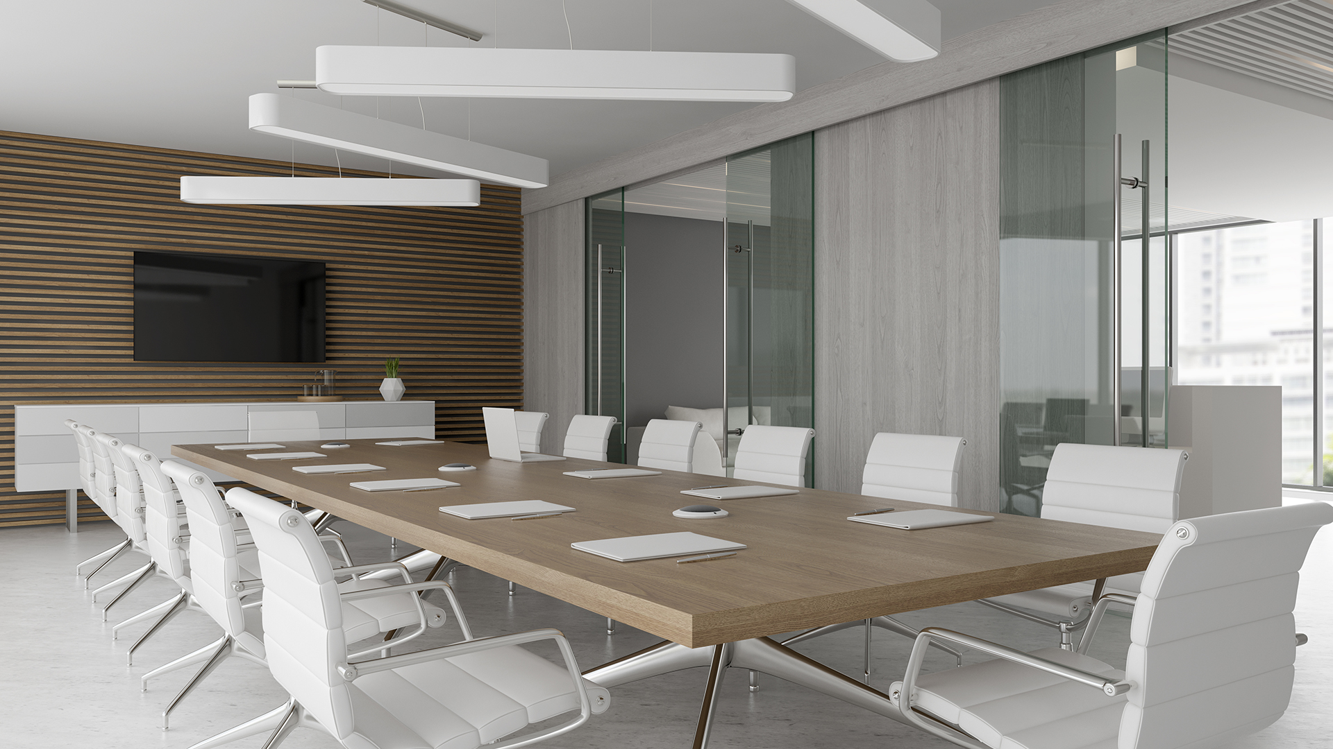 A modern conference room with a large wooden table surrounded by white office chairs. The room features a striped wood accent wall, a mounted flat-screen TV, glass doors, and sleek overhead lights.