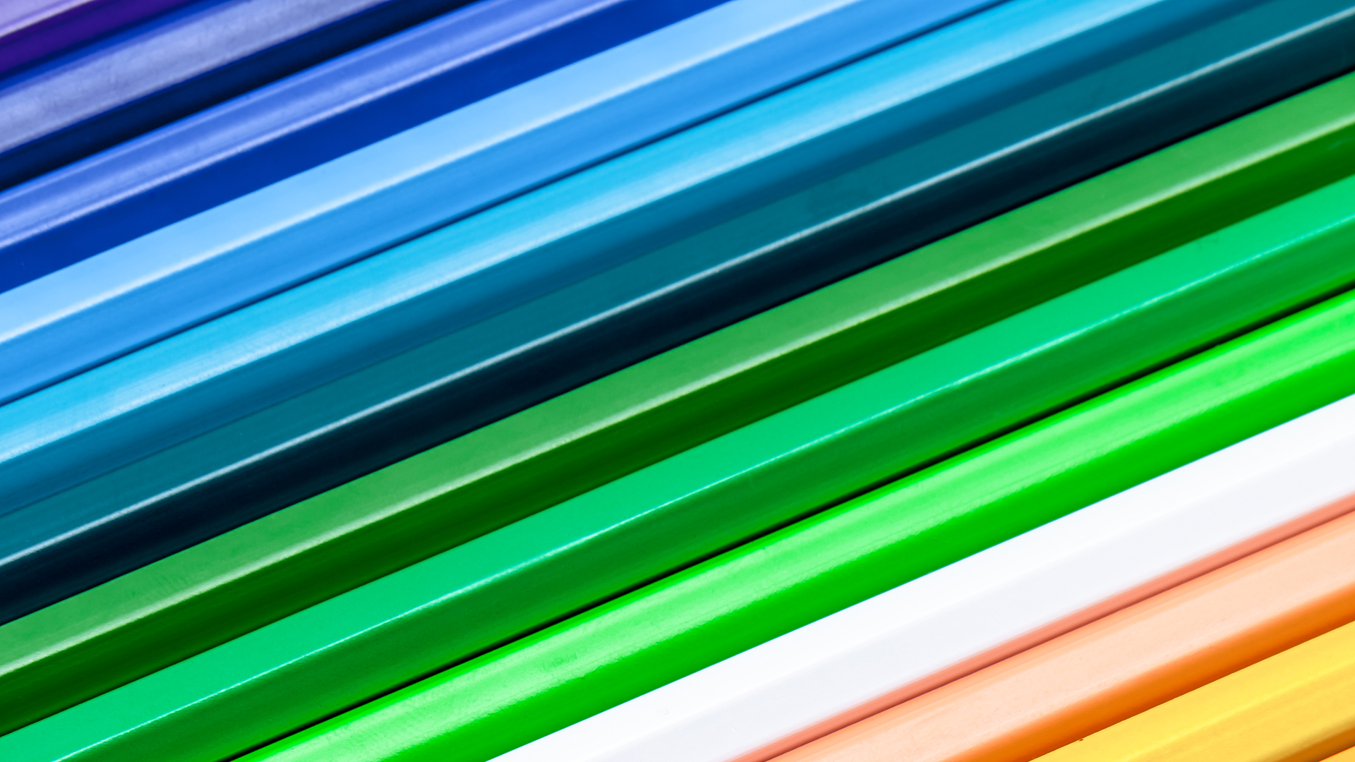 A close-up of colorful pencils arranged in parallel, featuring shades of blue, green, and other bright colors.