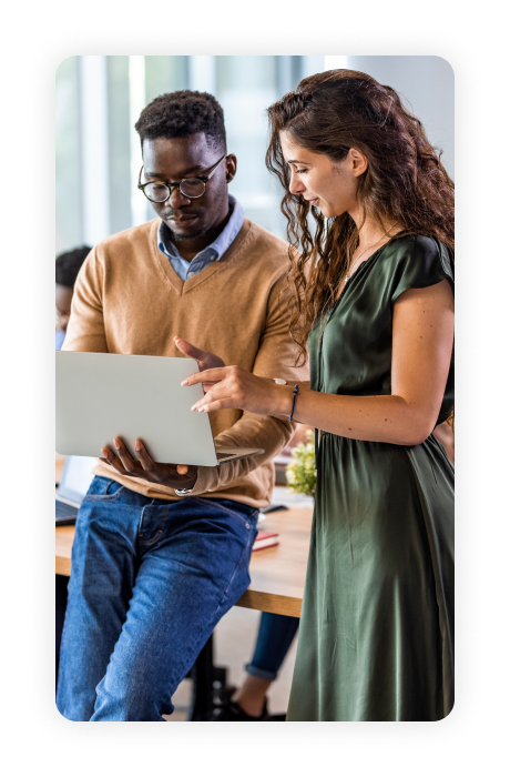 Two people looking at a laptop in an office.