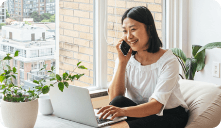 A woman smiling while using a mobile phone.