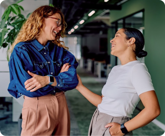 Two professional women enjoying a conversation in an earth green toned office.