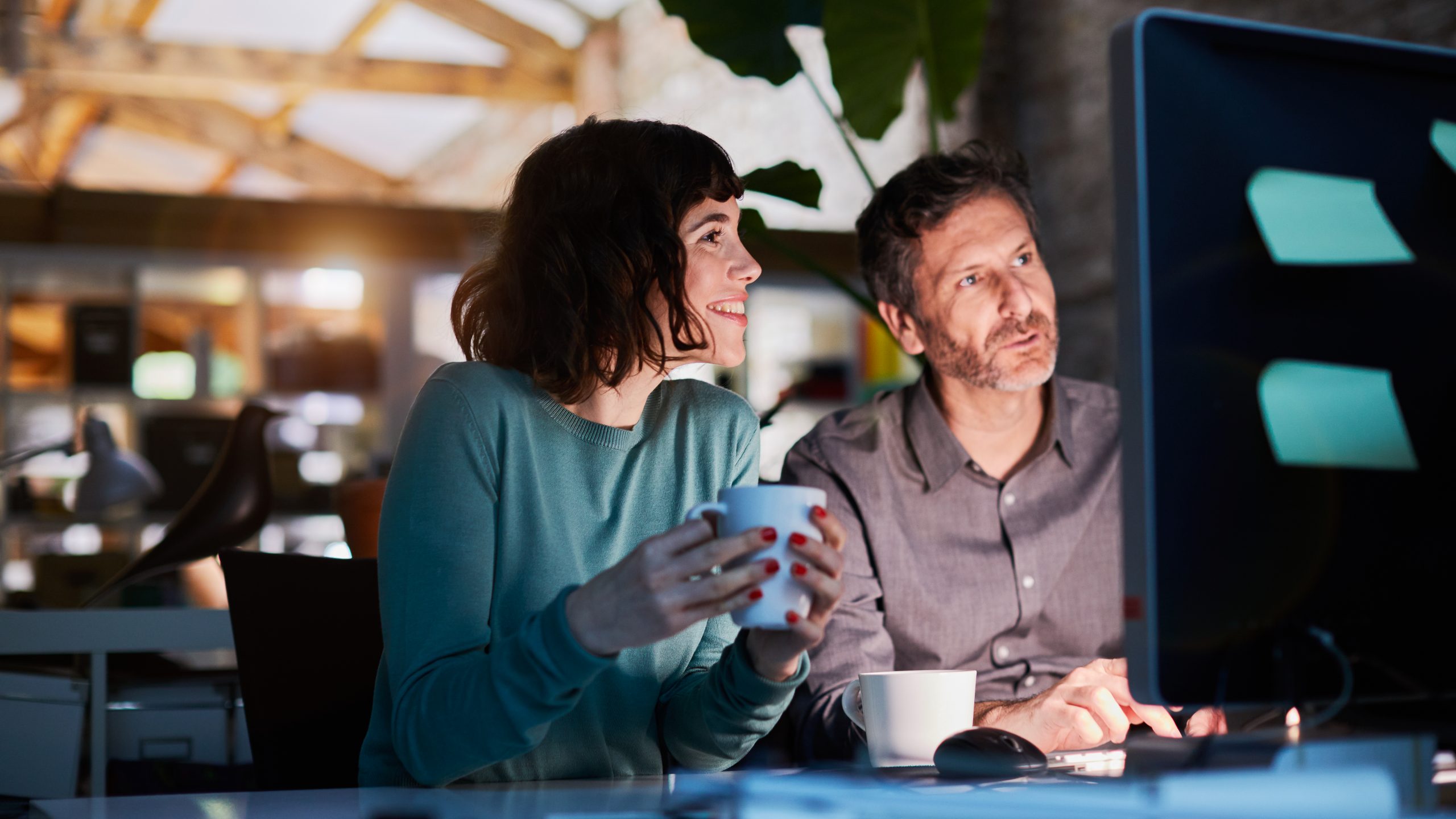 Two workers sharing a screen, managing their comms via digital signage content scheduling