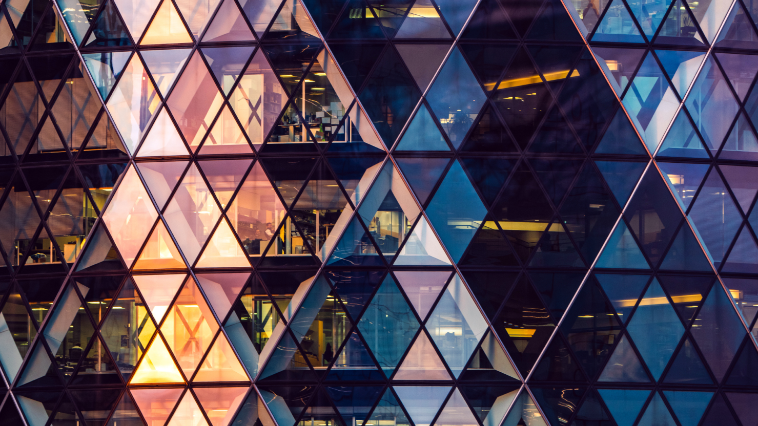 Glass building reflecting red and blue hues of the sunset.