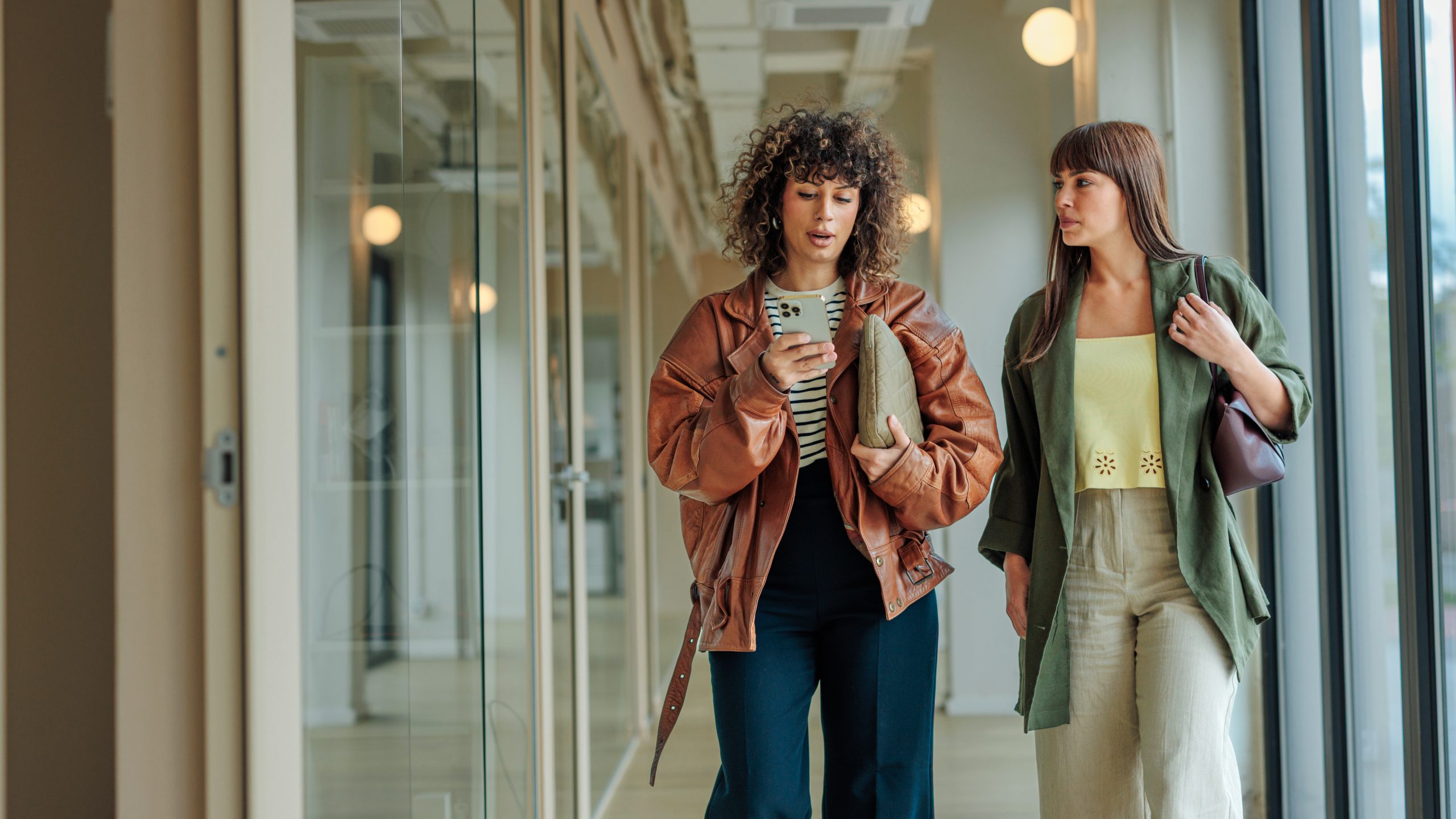 Two women walking along a corridor using digital wayfinding on a mobile app to find their way